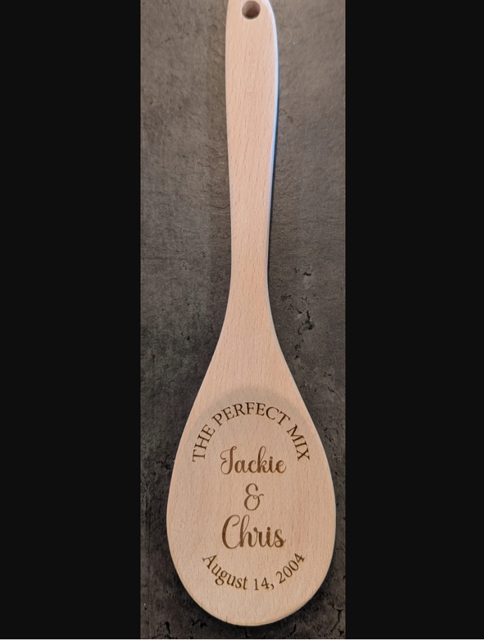 Wooden spoon with engraved text on a dark background