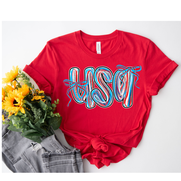 Red t-shirt with colorful 'USA' design, gray jeans, and yellow flowers on a white background