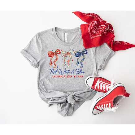 Gray t-shirt with colorful graphics and text, red sneakers, and red bandana on a white background